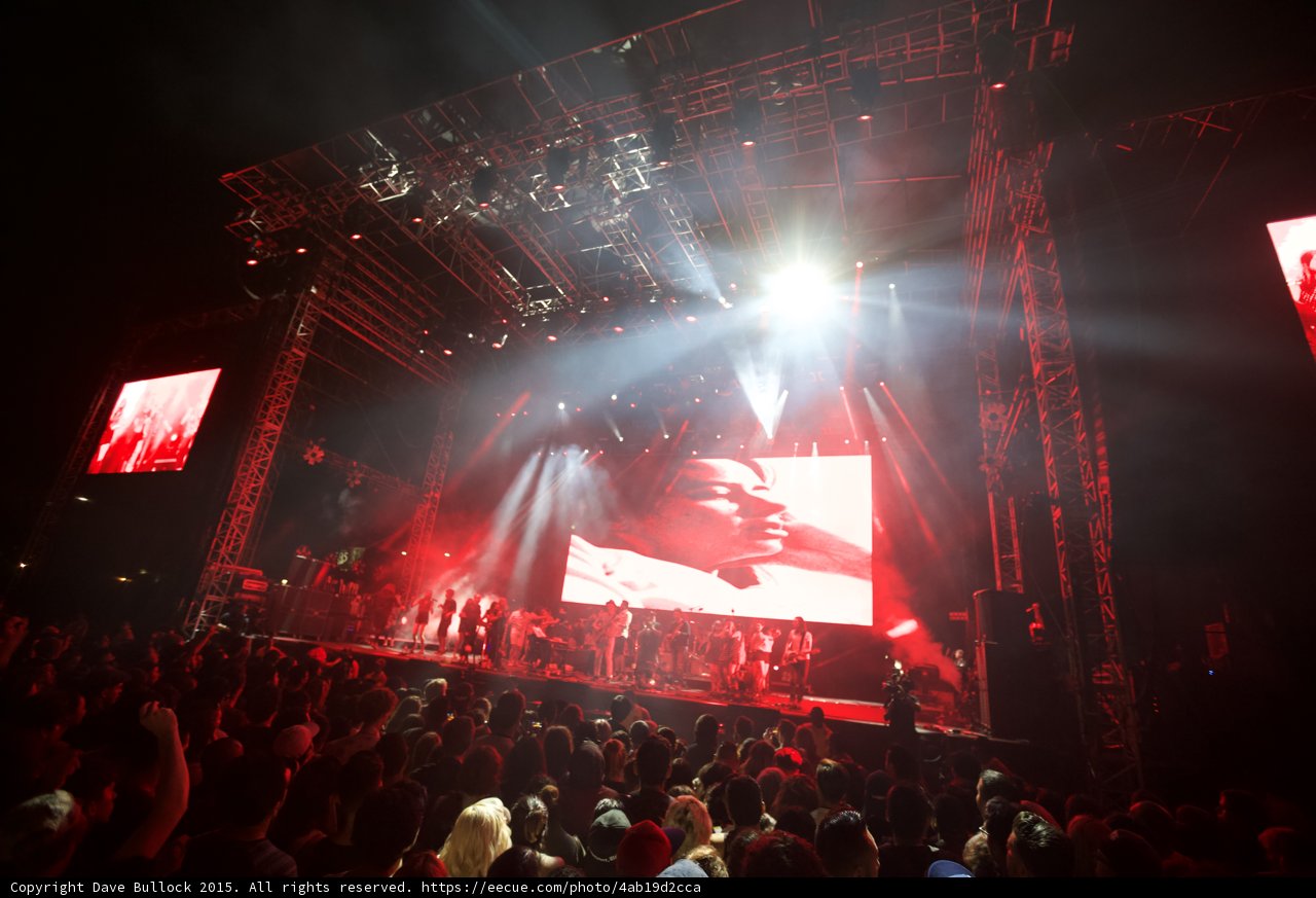 Belle and Sebastian Wide Stage Spotlight Flare Video Screen Face Red Lighting Blonde Woman Crowd