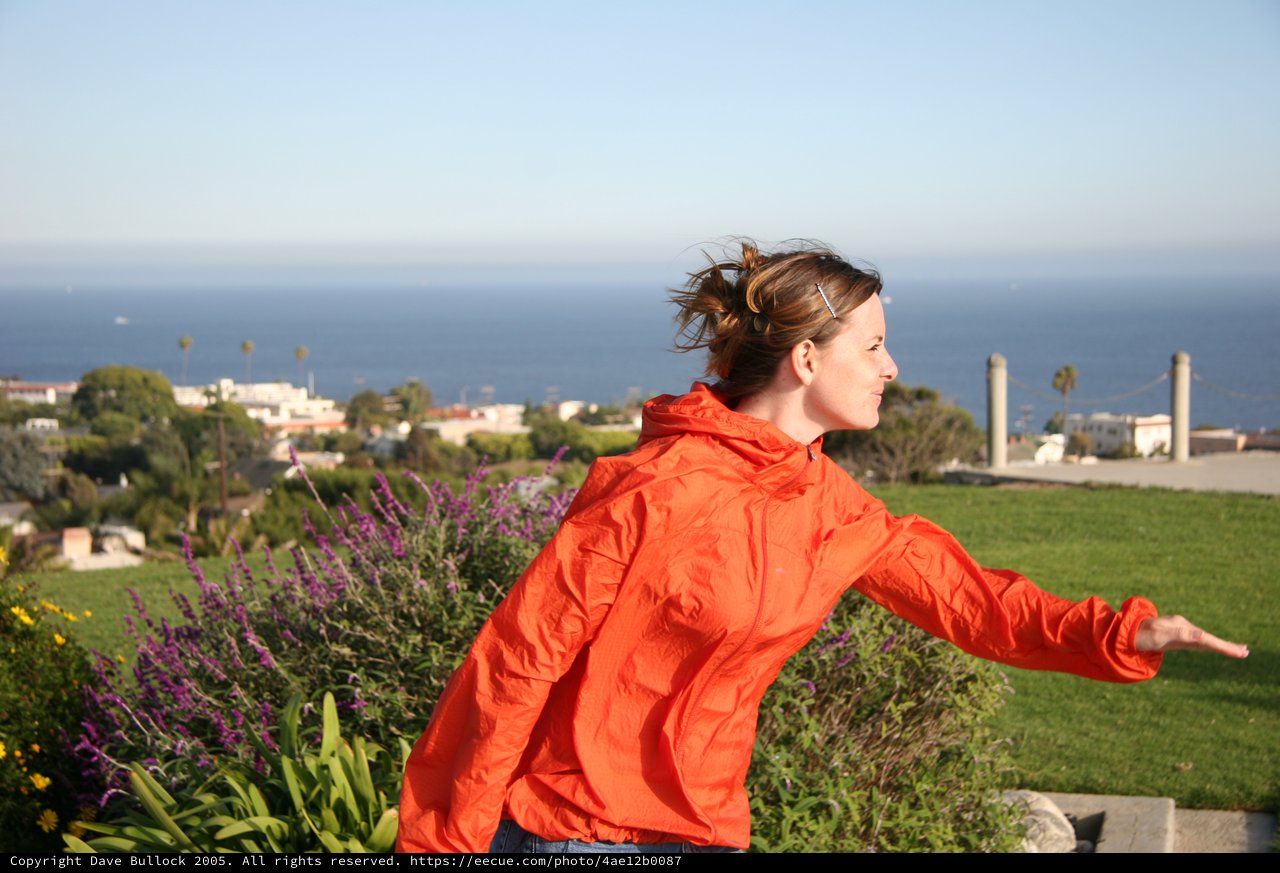 Woman in Red Jacket Embracing the Ocean Breeze