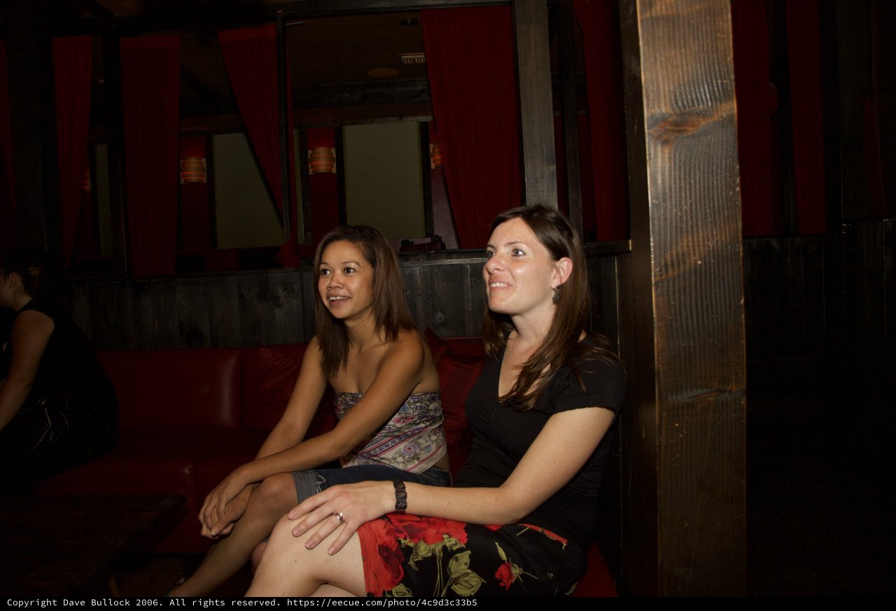 Two Women Relaxing in Dimly Lit Bar Booth