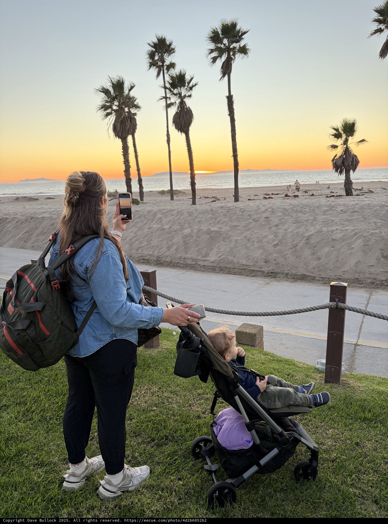 Mother Capturing Sunset Beach Moment with Child