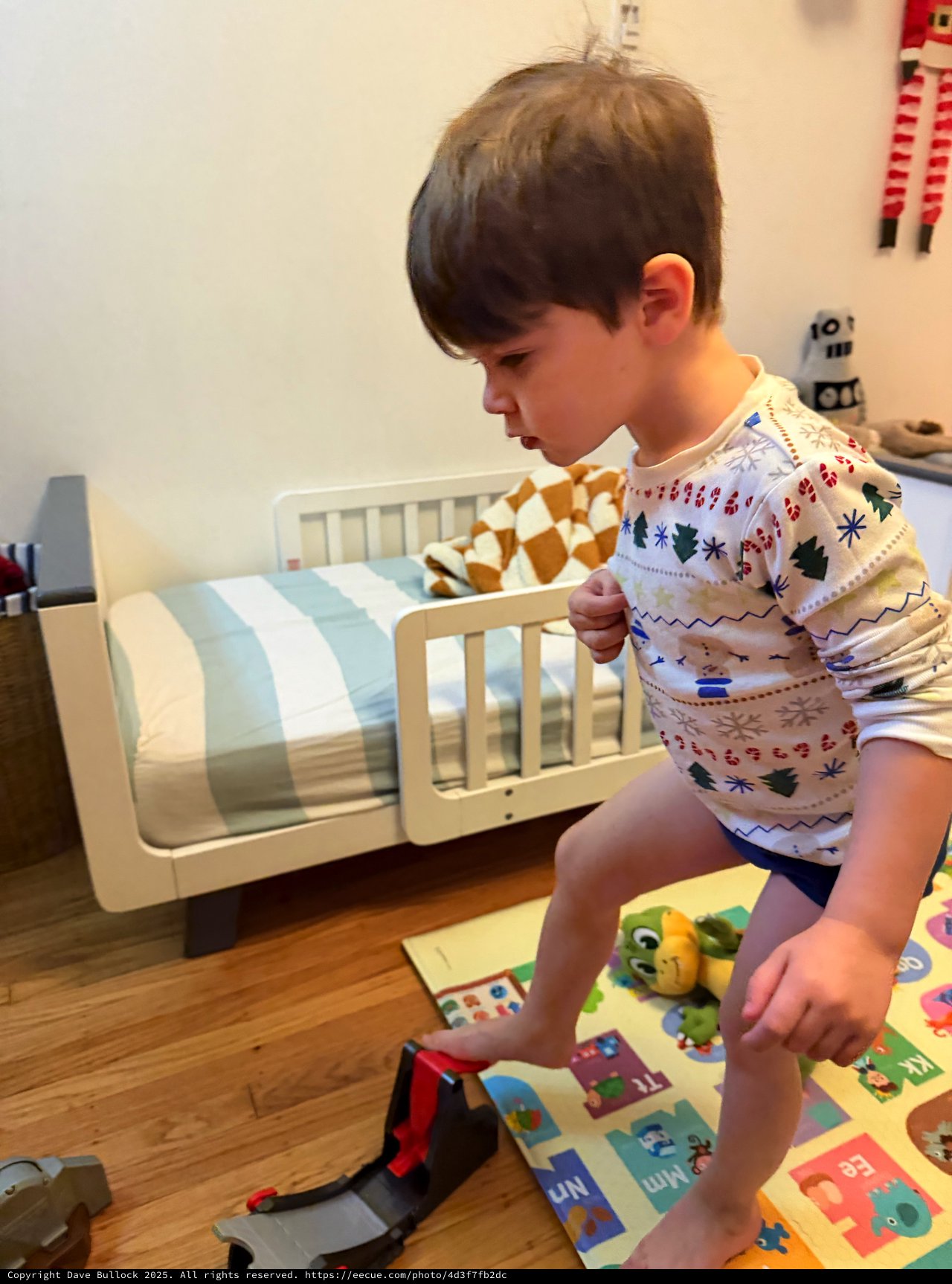 Young Boy Playing in Festive Pajamas on Bedroom Floor