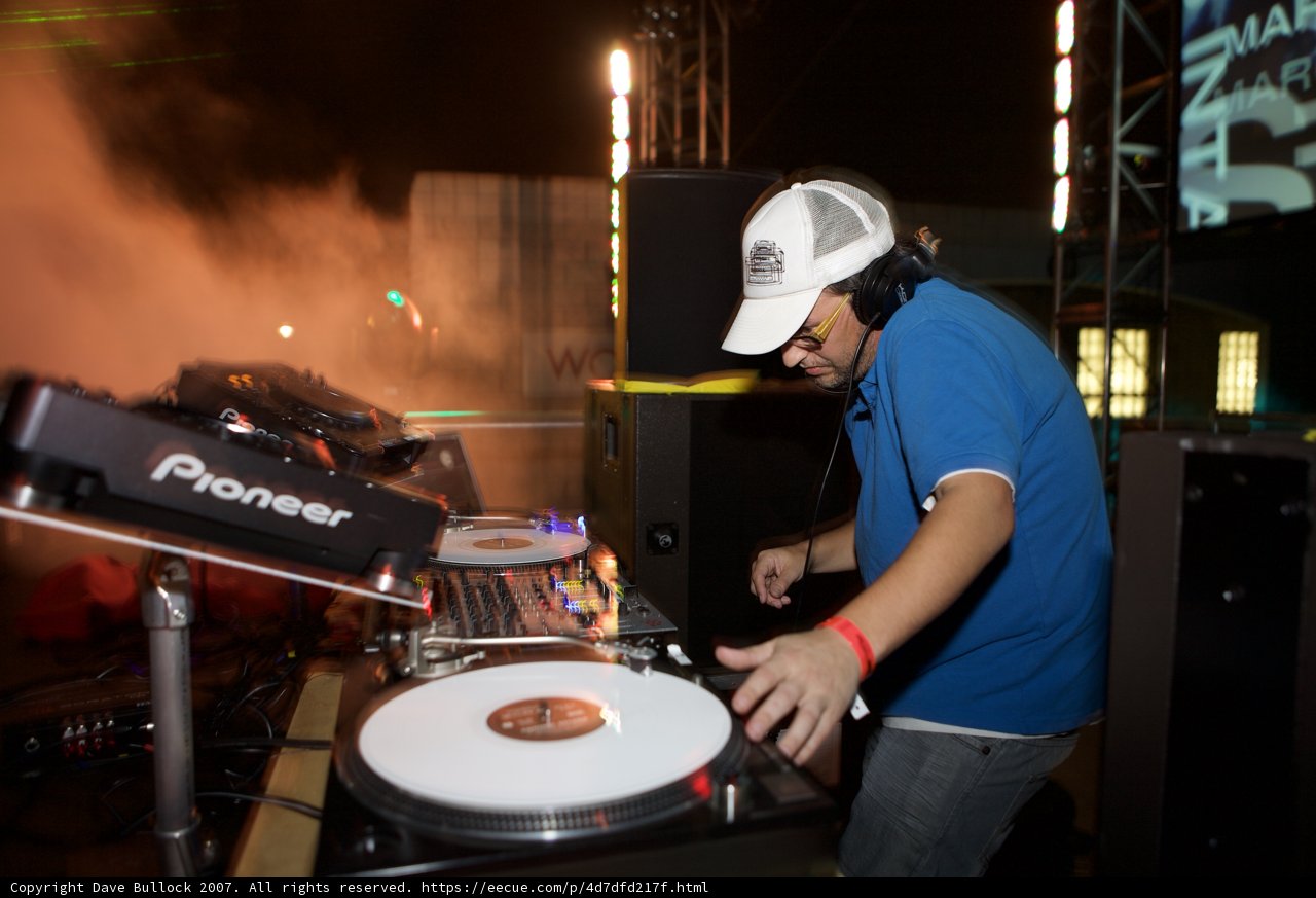 Entertaining the Crowd Caption: A deejay in a baseball hat plays music on his turntable, entertaining a crowd at a party in 2007.