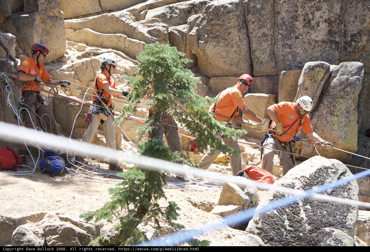 Orange-Shirted Men Scaling Rocks