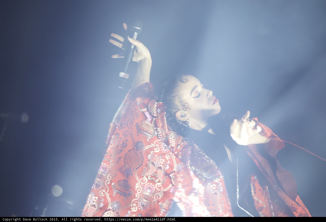 FKA twigs Dramatic Backlit Looking Upward Microphone Raised Red Brocade Kimono Baby Hairs Expressive Hand