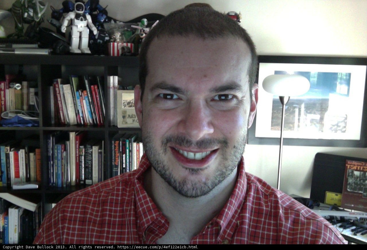 Man Smiling in Front of His Book Collection