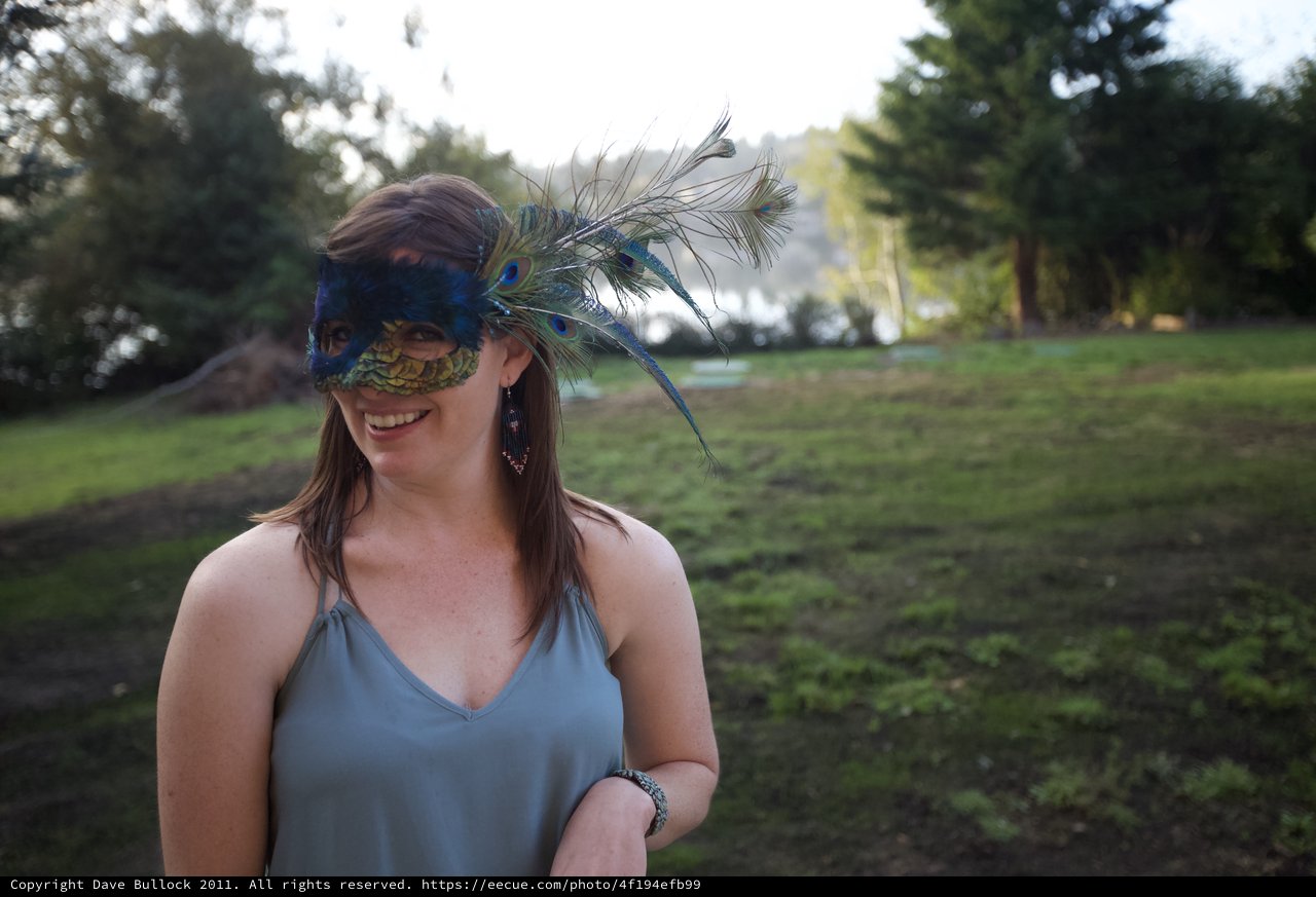 Smiling Woman in Peacock Masquerade Mask Outdoors