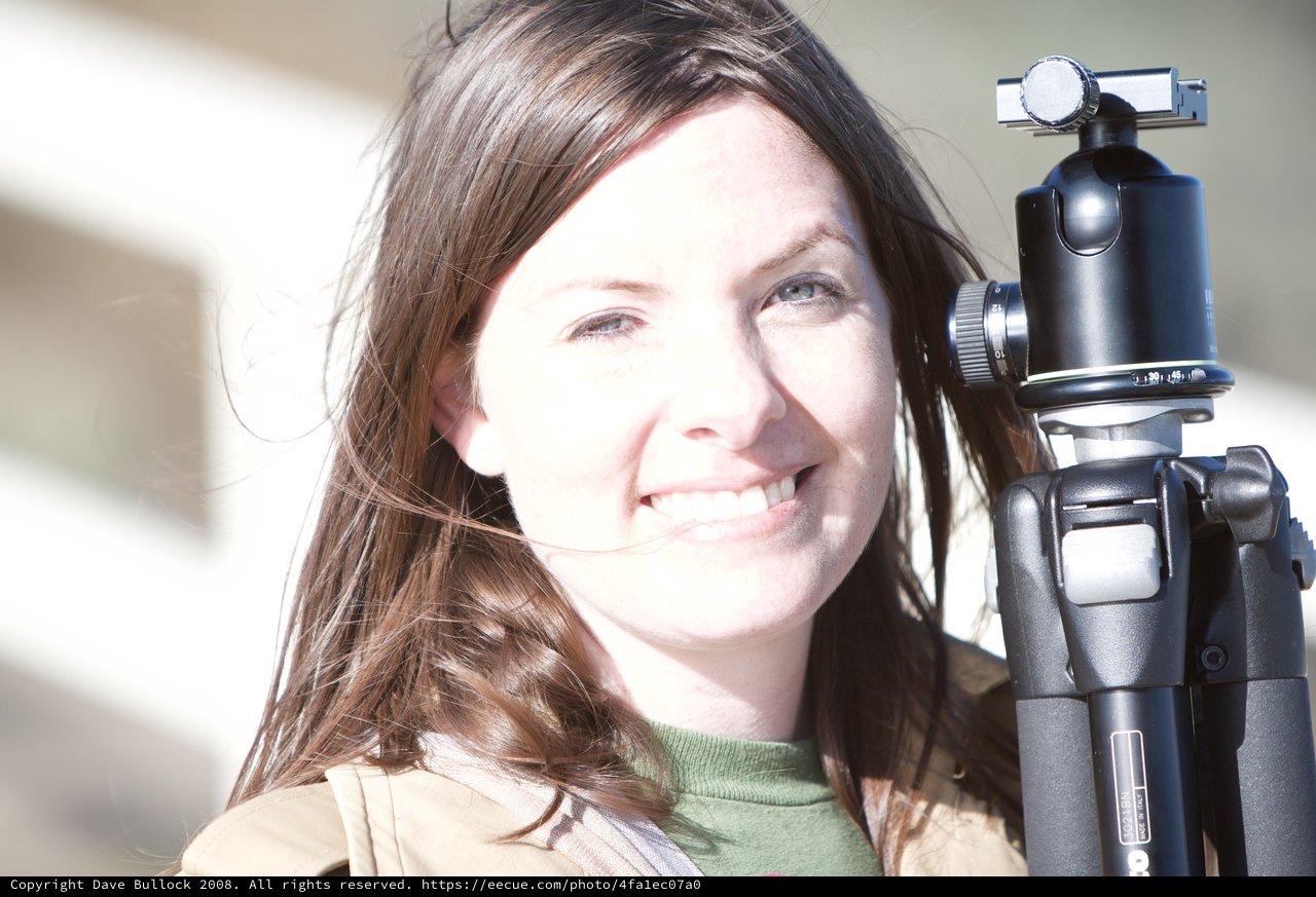 Smiling Photographer Holding Tripod in Bright Sunlight