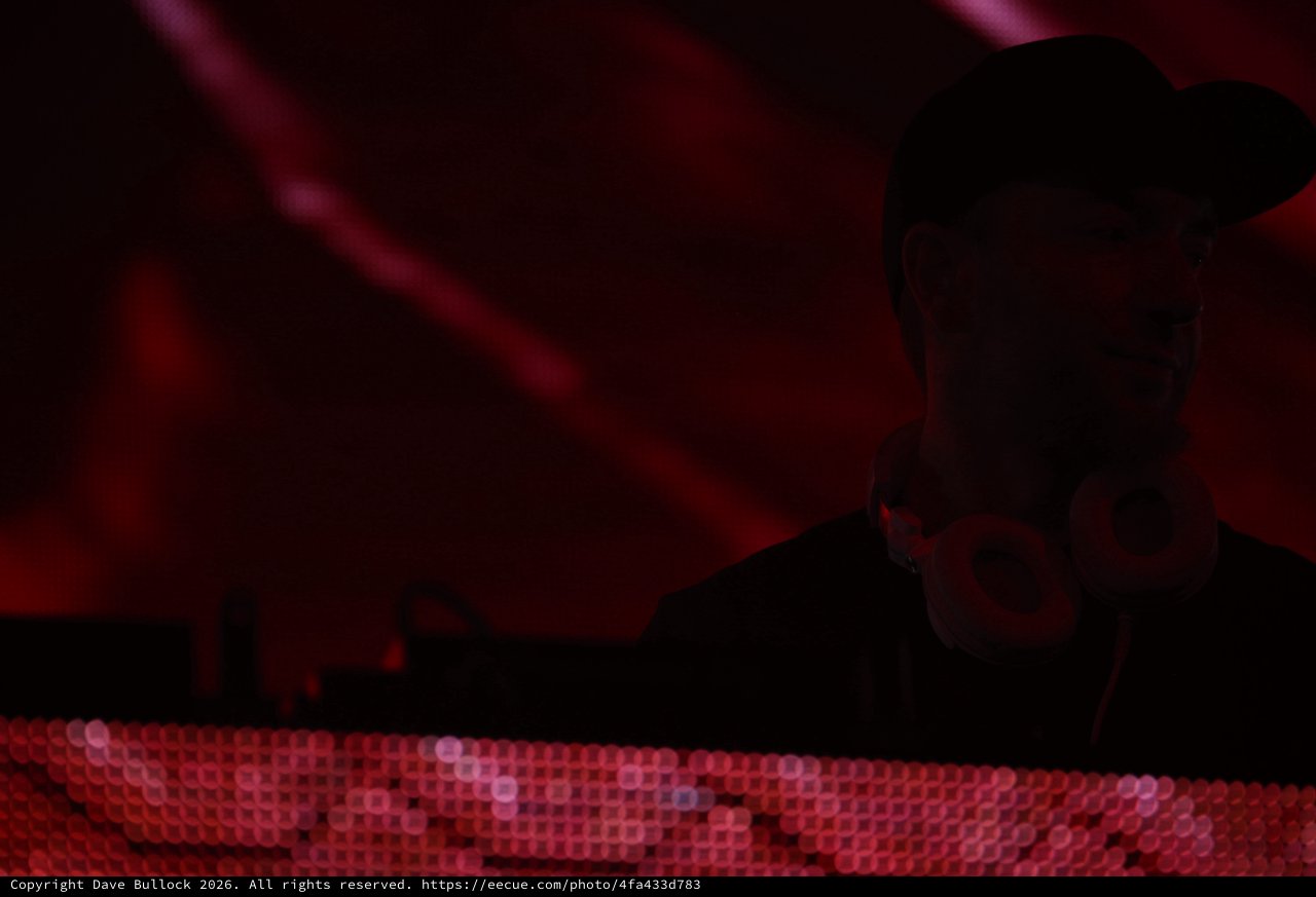 Silhouetted DJ Performing Under Crimson Stage Lights