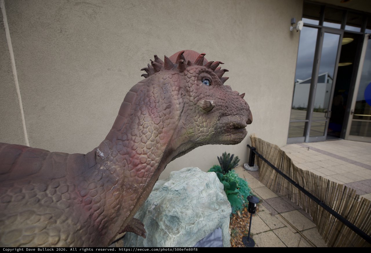 Whimsical Dinosaur Statue at Modern Building Entrance