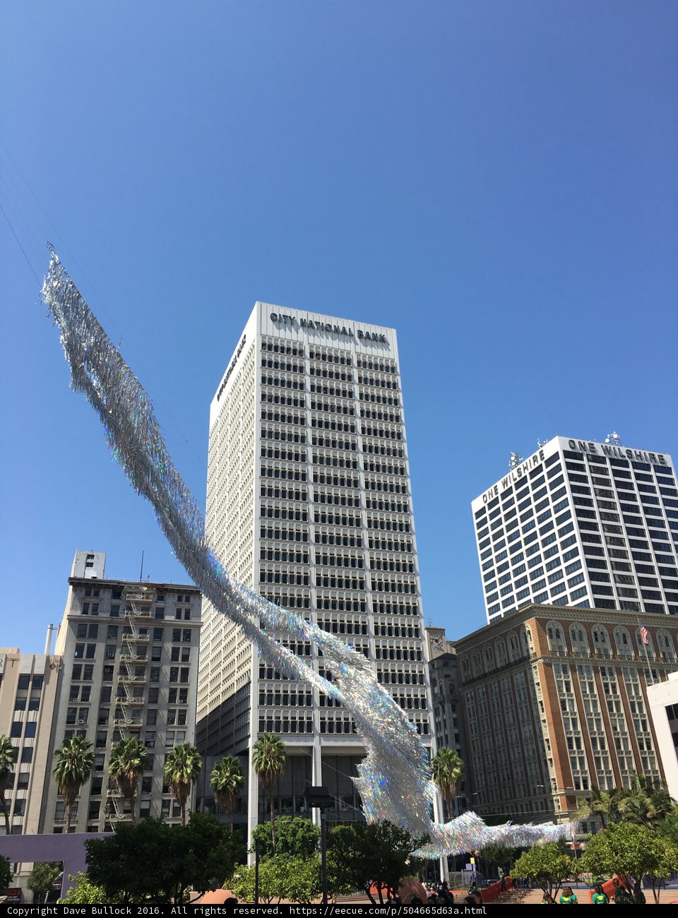 White sculpture standing tall in front of high rise building