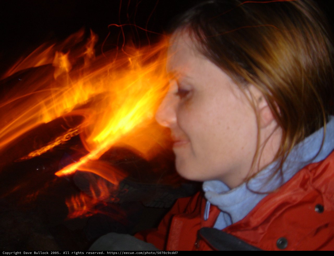 Woman Gazing Into Campfire on Dark Night
