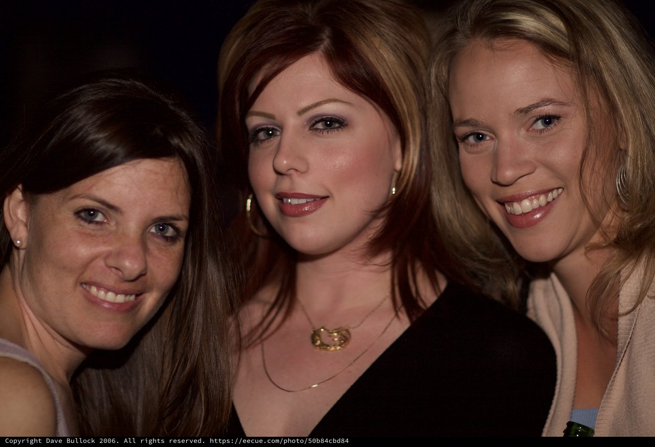 Three Friends Smiling Together at a Nighttime Event