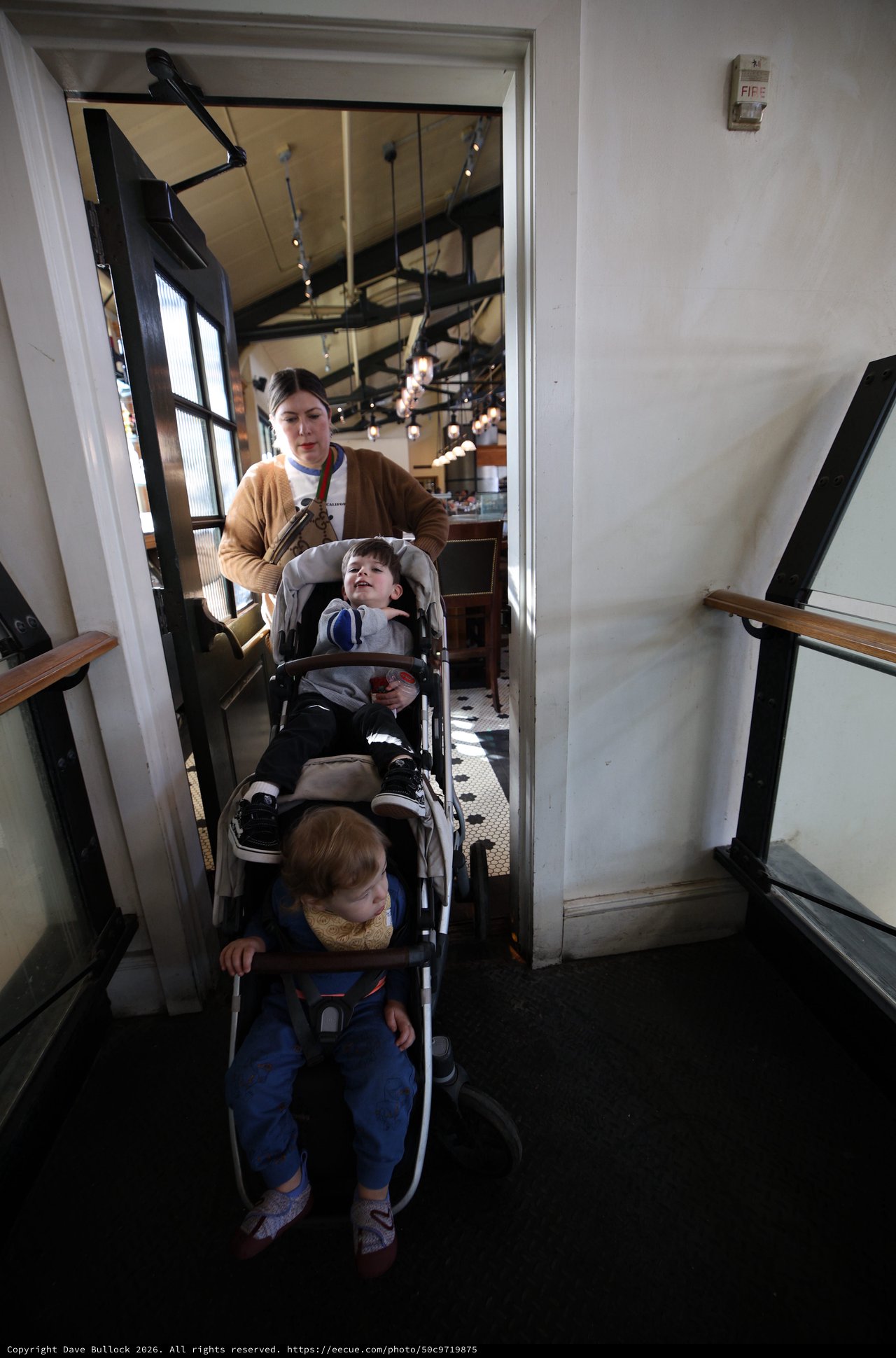 Parent Navigating Narrow Restaurant Stairwell with Double Stroller