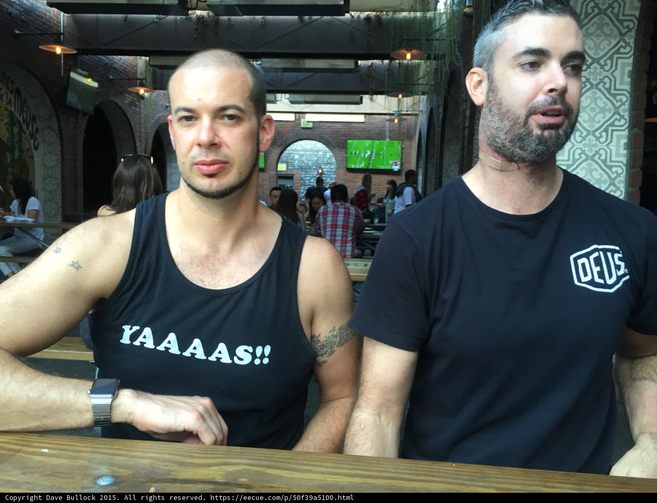 Two Friends Enjoying a Beer at a Wood Table