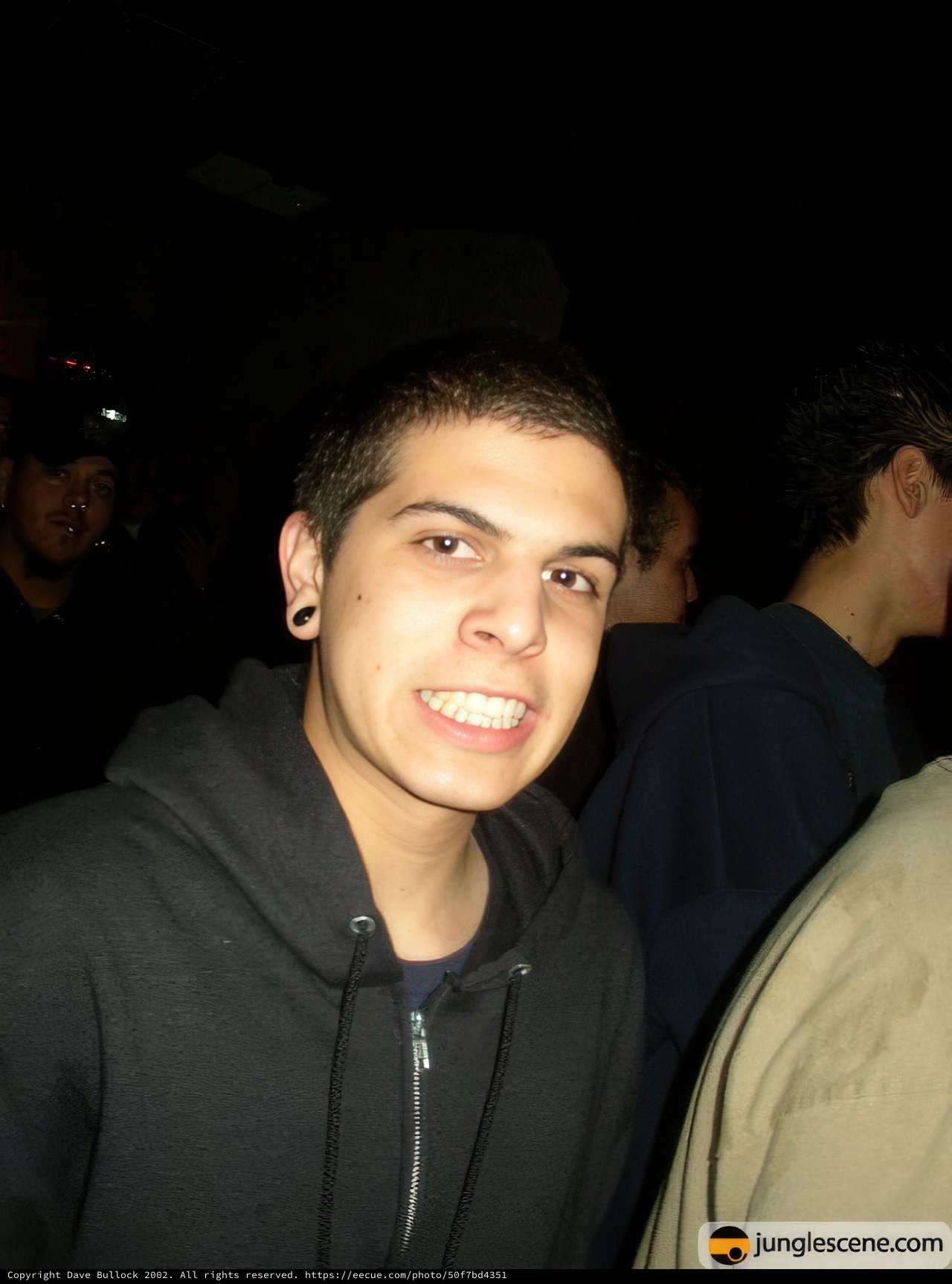 Man in Black Hoodie Poses with Two Friends