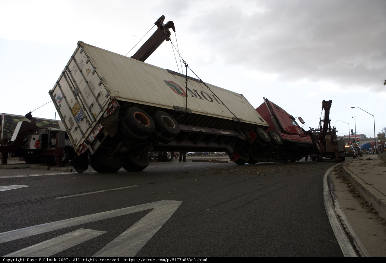 Overturned truck being lifted over street