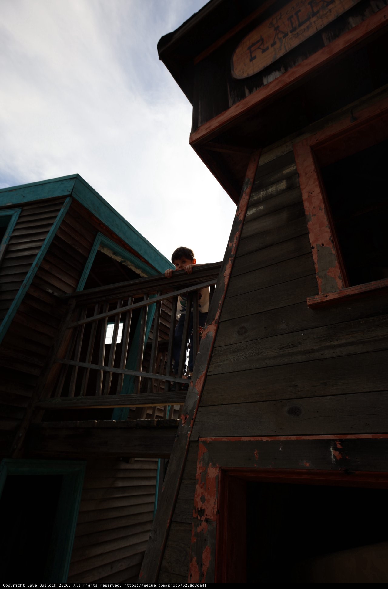 Child Peering from Weathered Wooden Balcony at Dusk