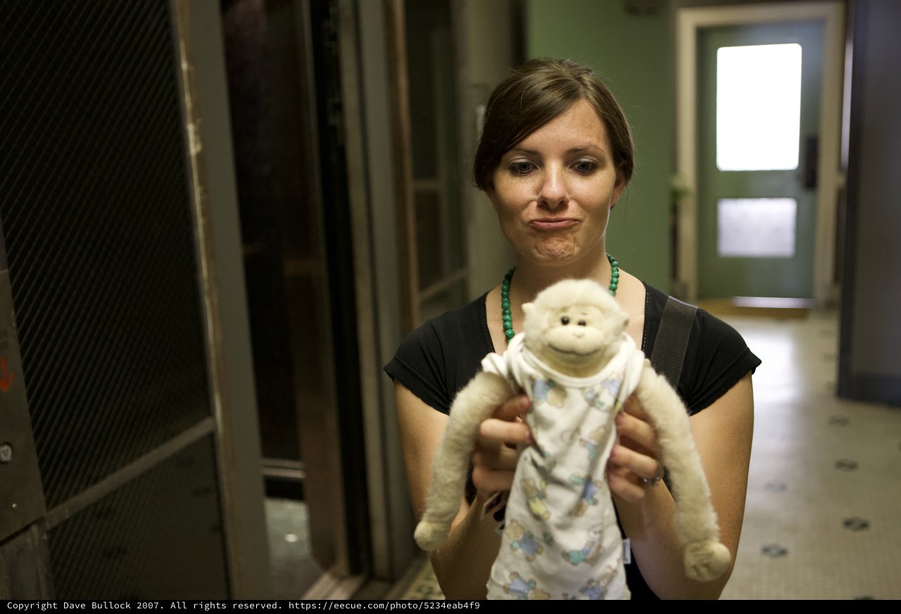 Woman Holds Stuffed Monkey Toy with Wistful Expression
