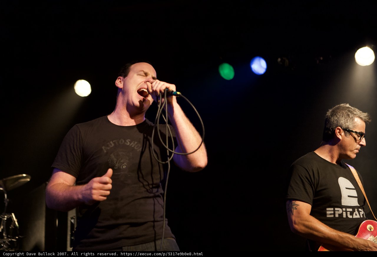Two Men on Stage Singing with Microphones