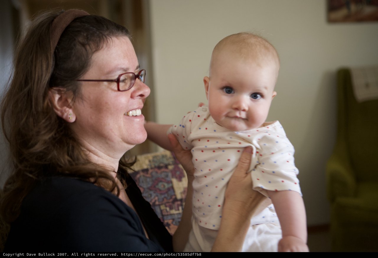 Joyful Mother Holds Smiling Baby Indoors
