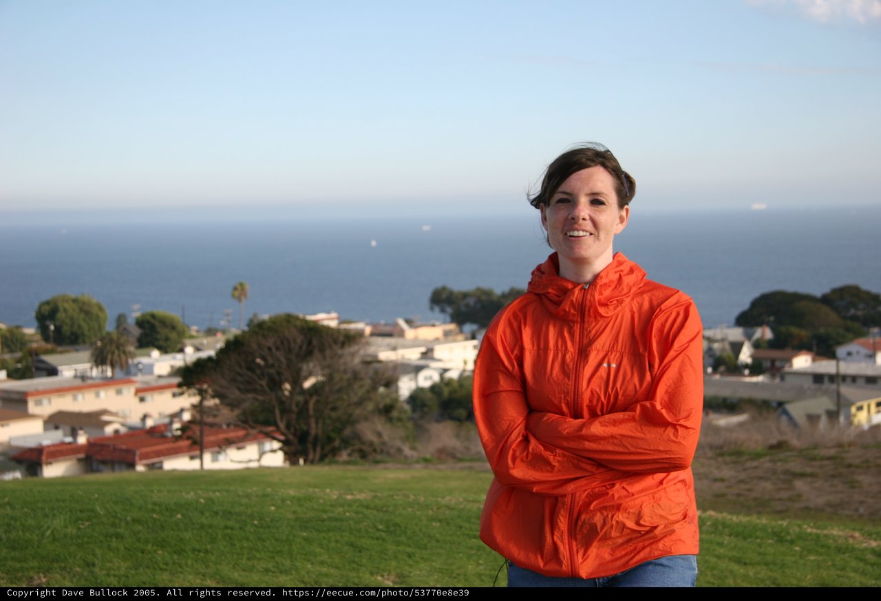 Woman in Orange Jacket Overlooking Coastal Town
