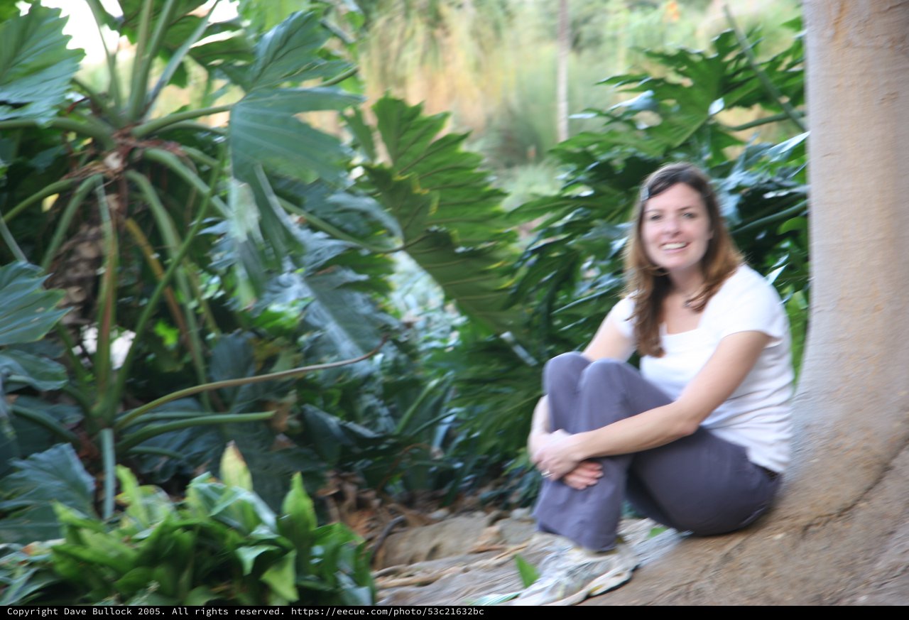 Woman Smiling Among Lush Tropical Garden Foliage