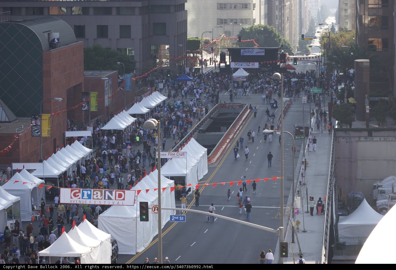 The Metropolis March Caption: A sea of people marching through the city streets on a detour, passing by tents and hydrants, amidst the roar of traffic lights and the hum of urban energy.