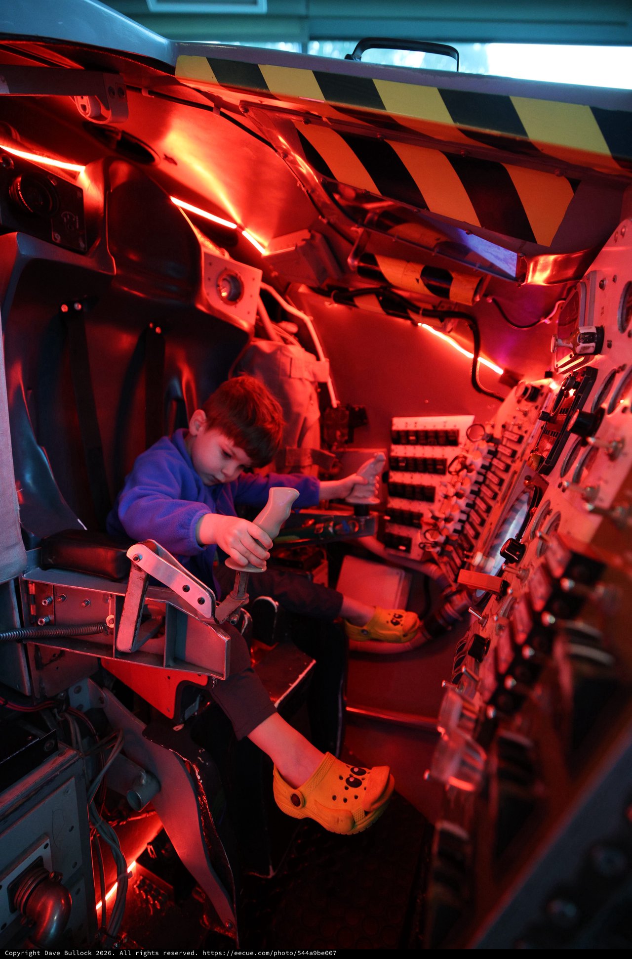 Young Visitor Explores Spacecraft Interior Under Red Emergency Lighting