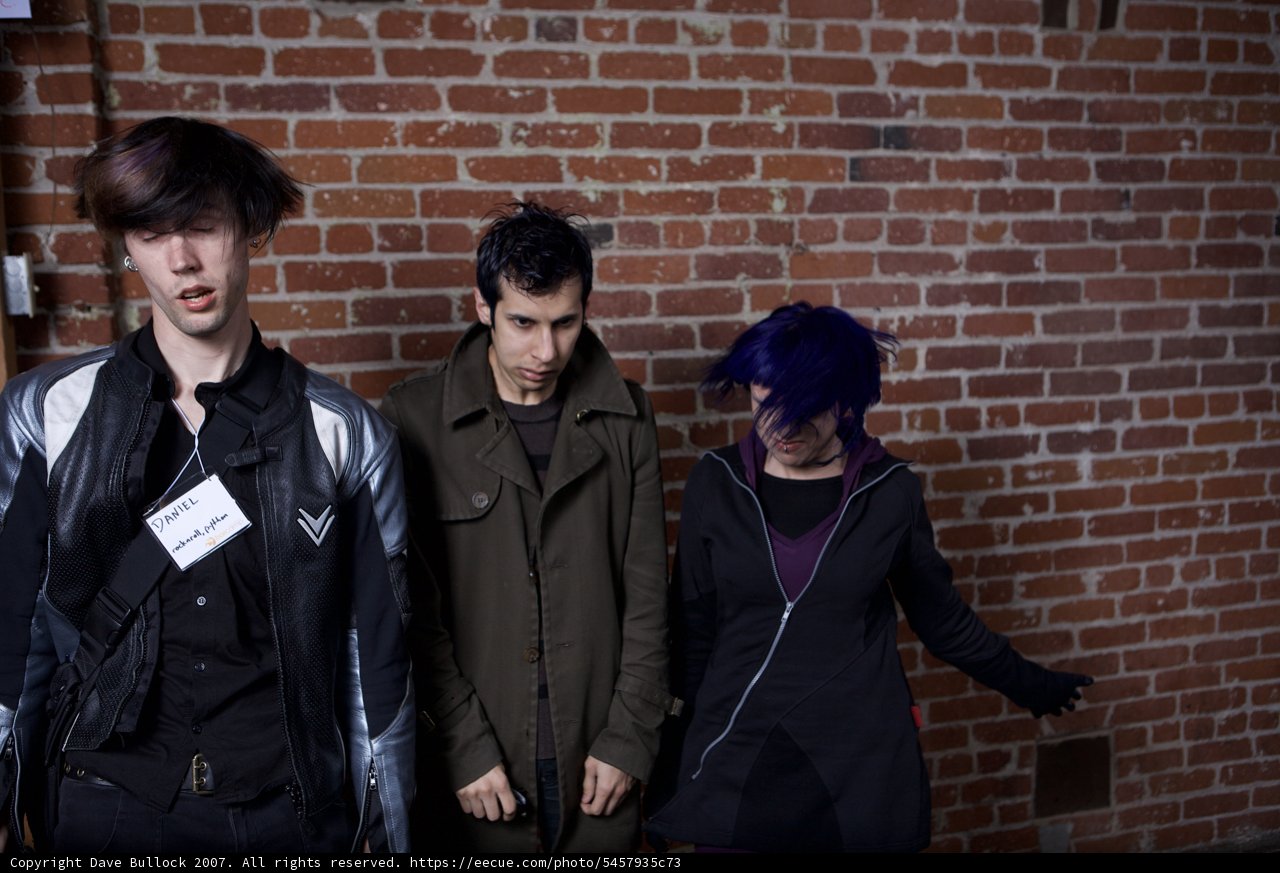 Three Young Adults Posed Next to Brick Wall