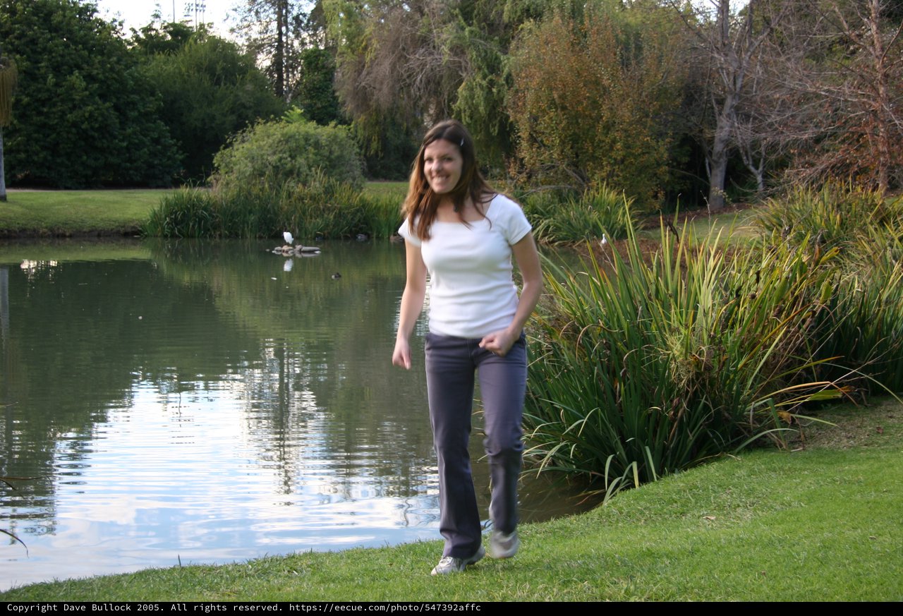 Woman Smiling by Tranquil Park Pond at Dusk