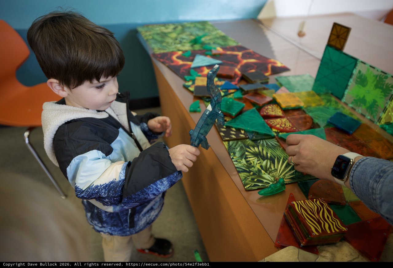 Young Child Explores Dinosaur Toy at Interactive Play Table