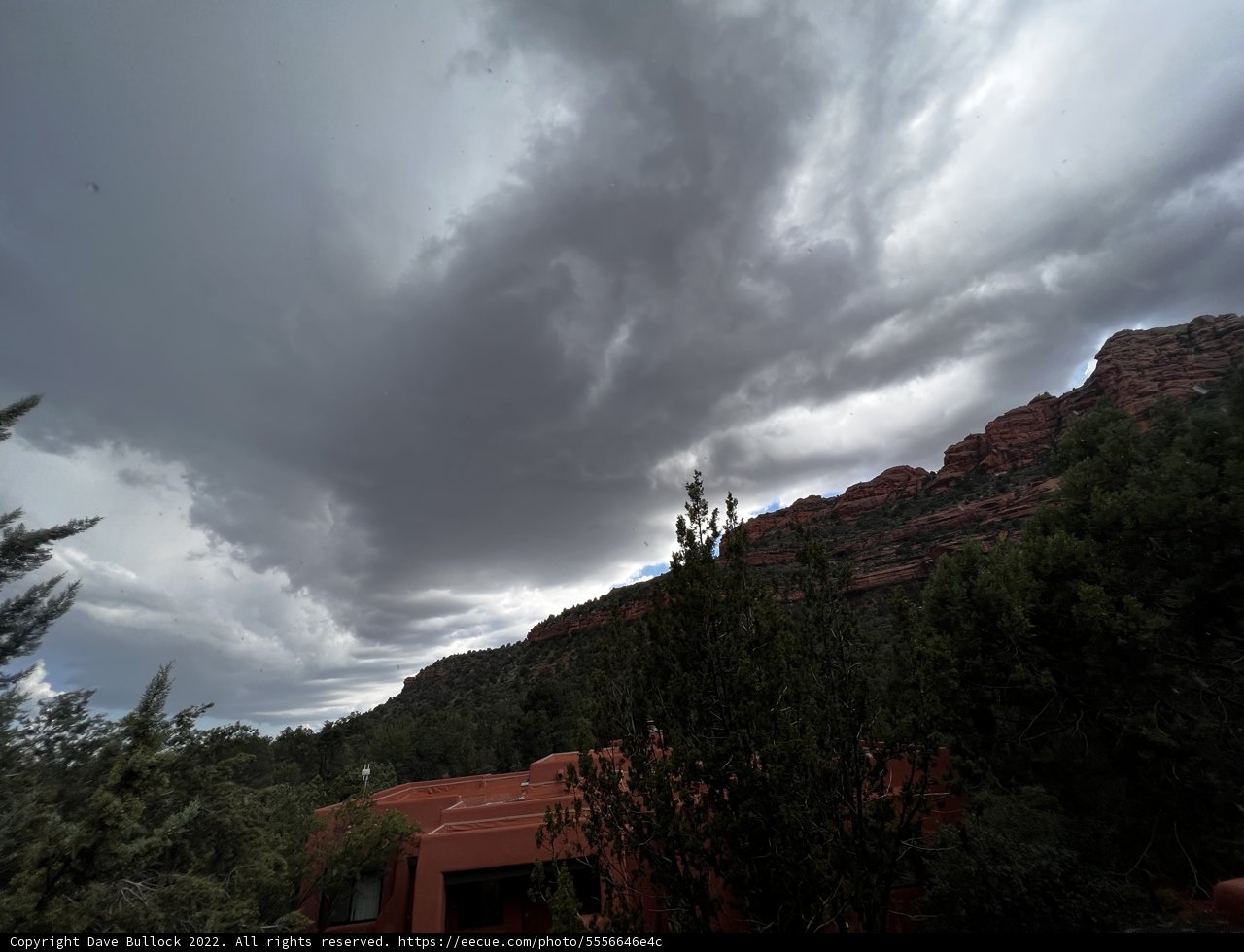 Red House Sheltered by Majestic Mountains and Stormy Sky