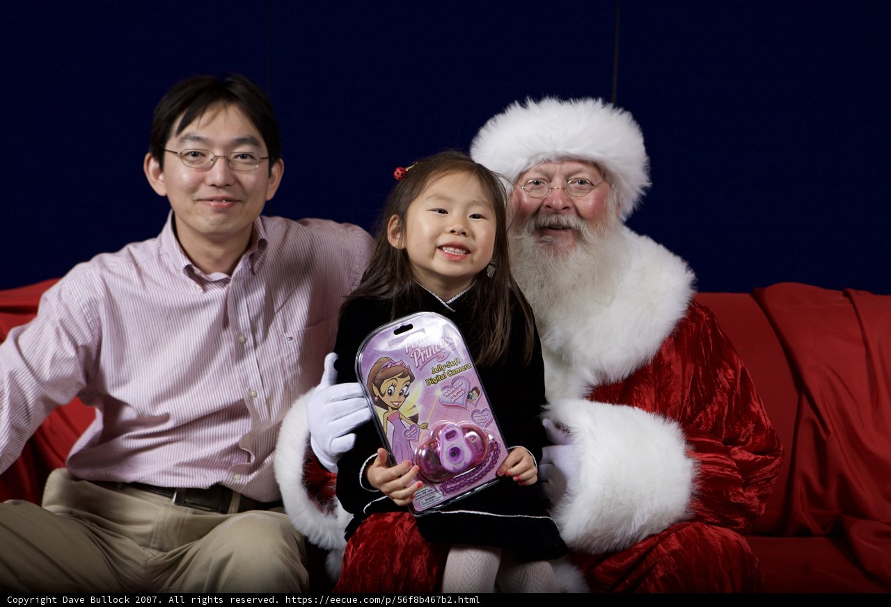 Santa Claus joins a little girl and her friend for the APC Christmas party