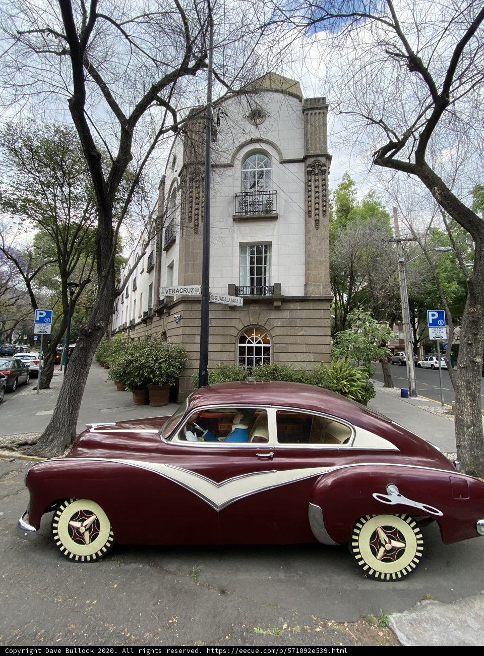 Maroon Coupe Parked in Front of Towering Architecture