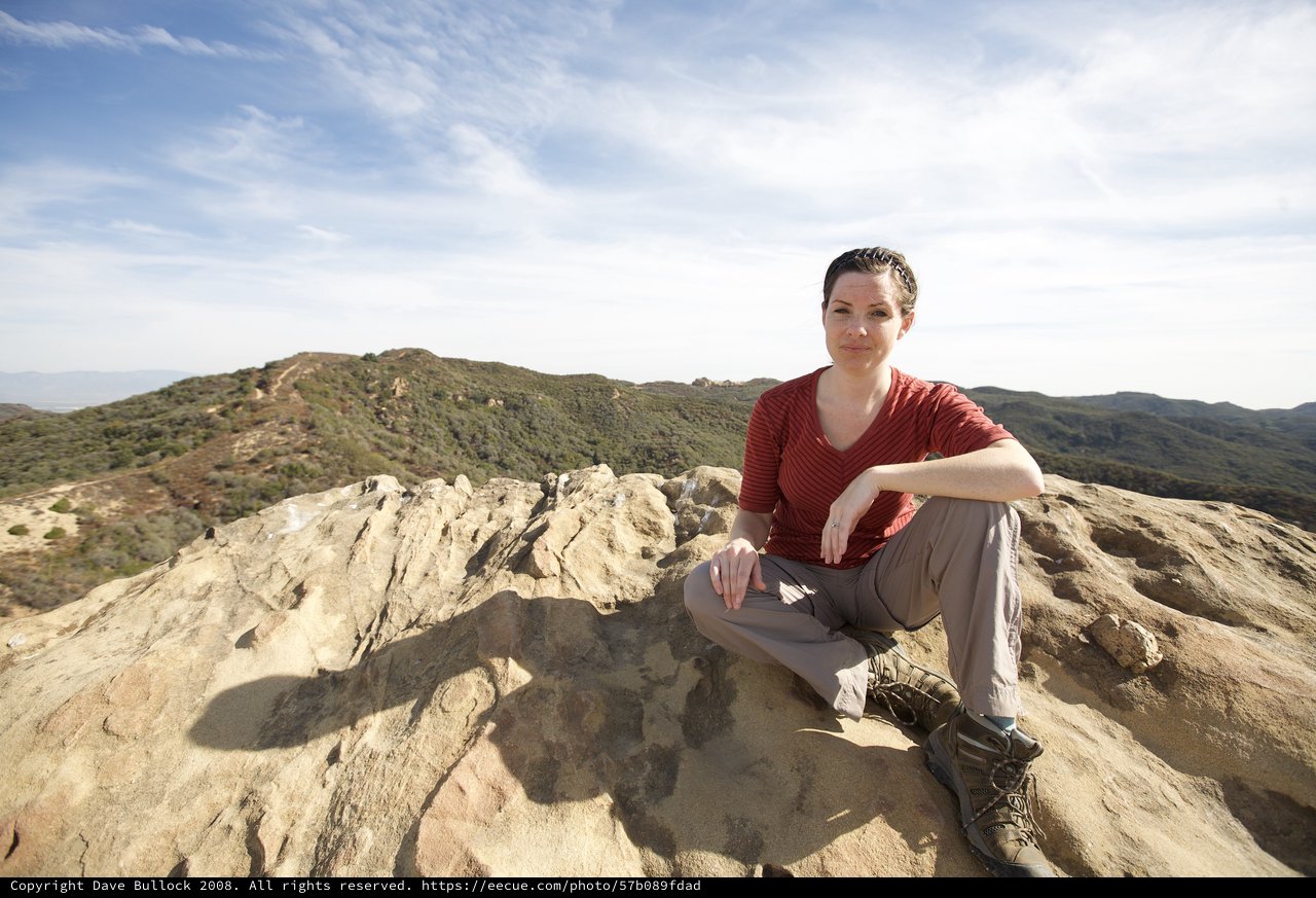 Hiker Rests Atop Rocky Summit with Mountain Vista