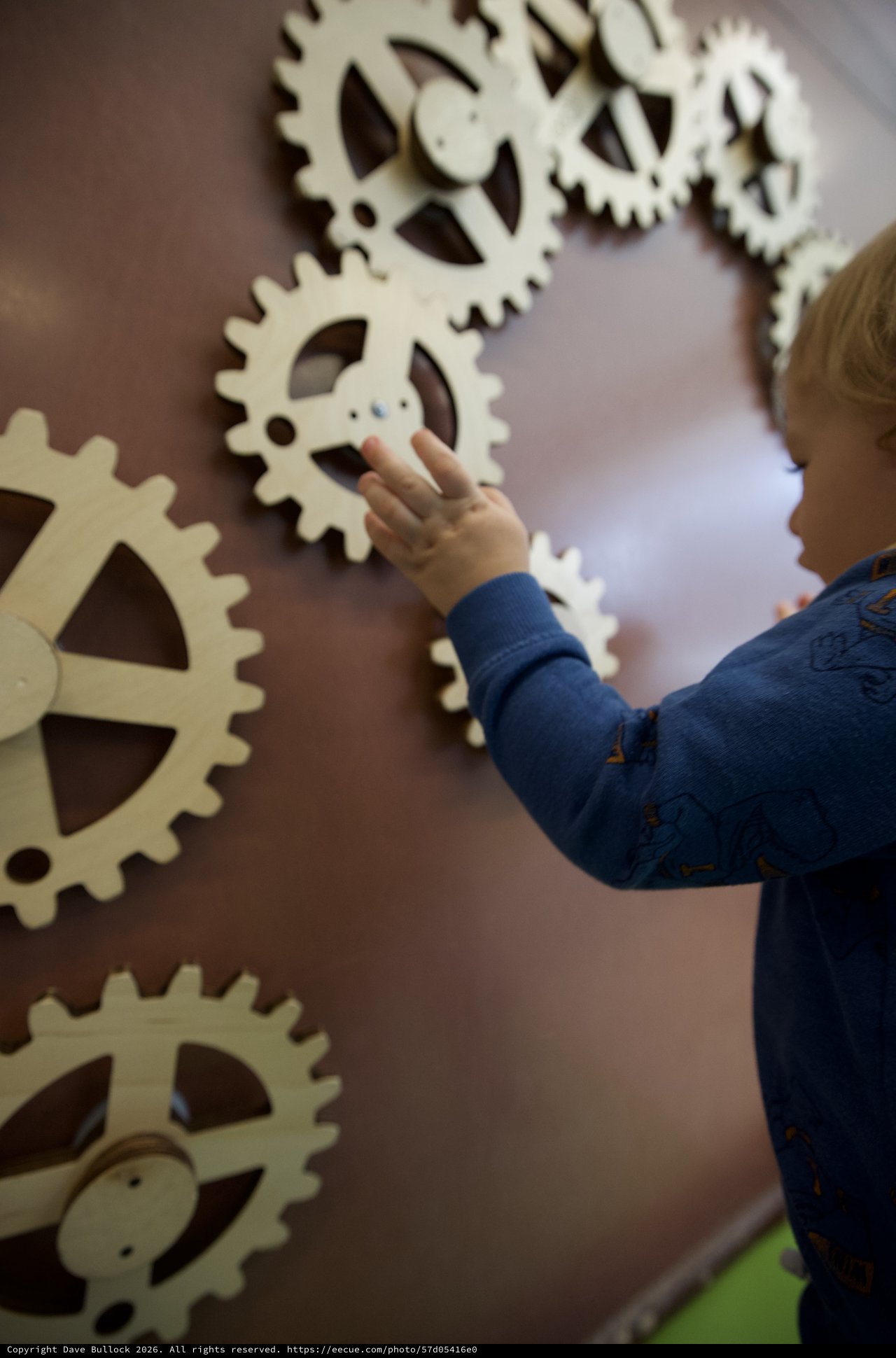 Child Exploring Interactive Gear Wall at Museum