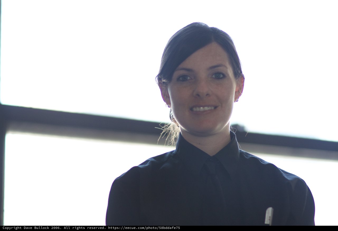 Woman in Dark Shirt Smiling Against Bright Window