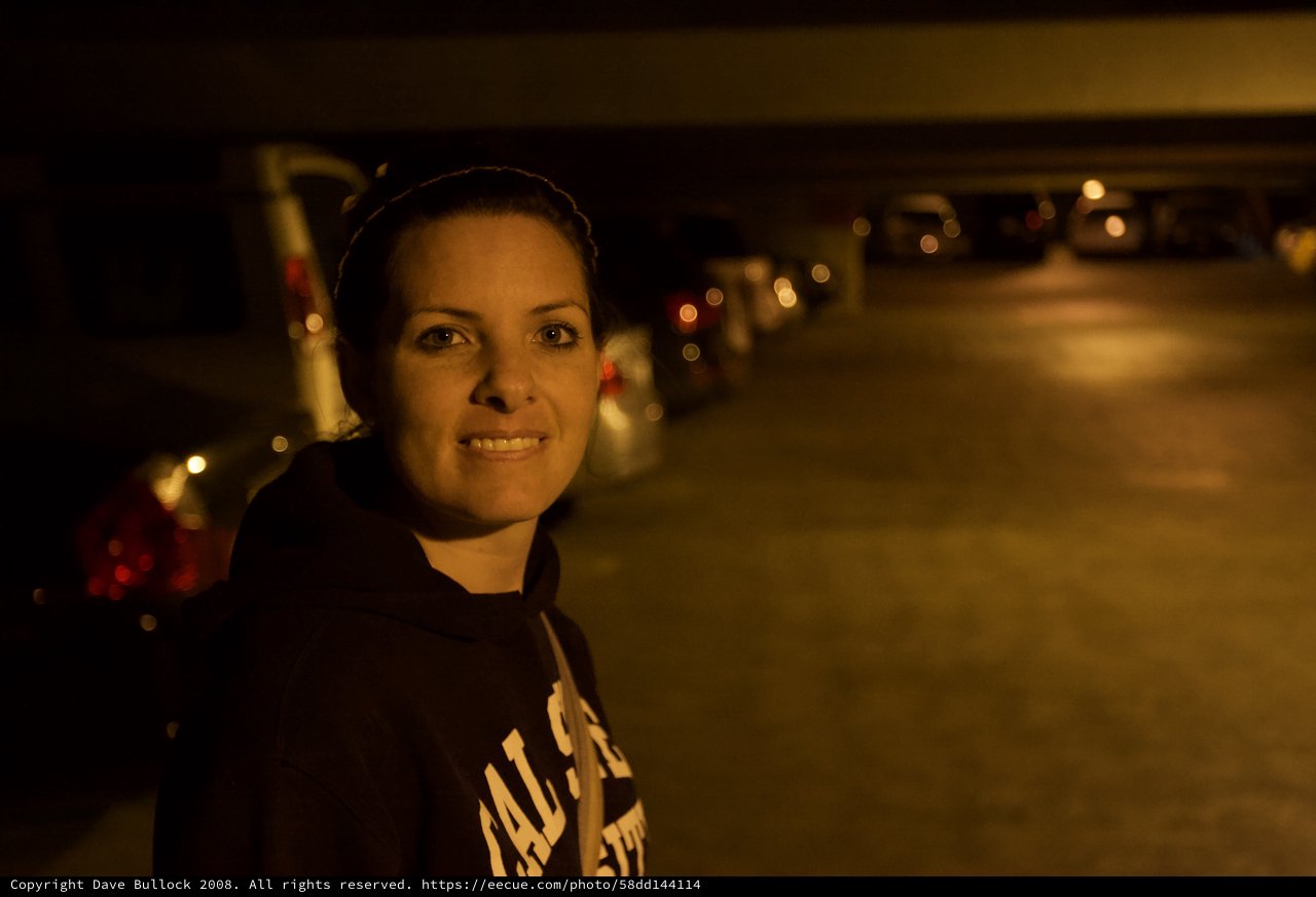 Woman Smiling in Dimly Lit Parking Garage at Night