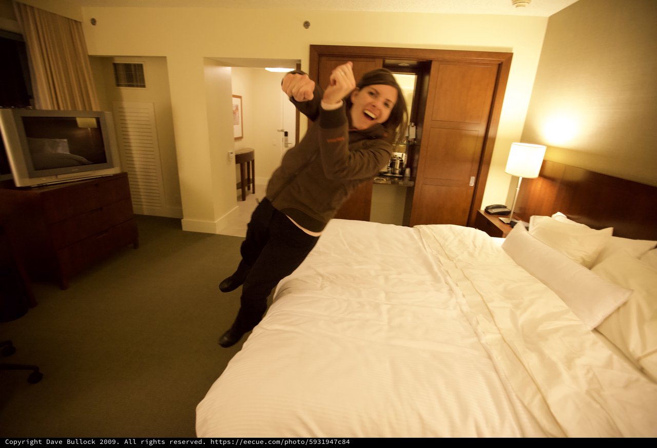 Excited Woman Leaping Onto Hotel Bed in San Francisco