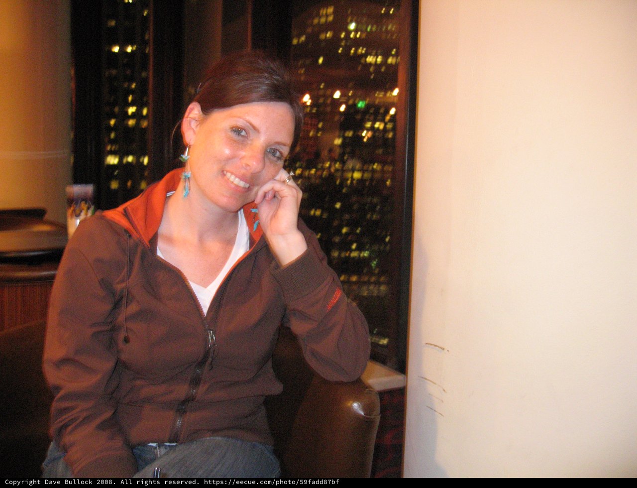 Smiling Woman at Urban Bar with City Lights