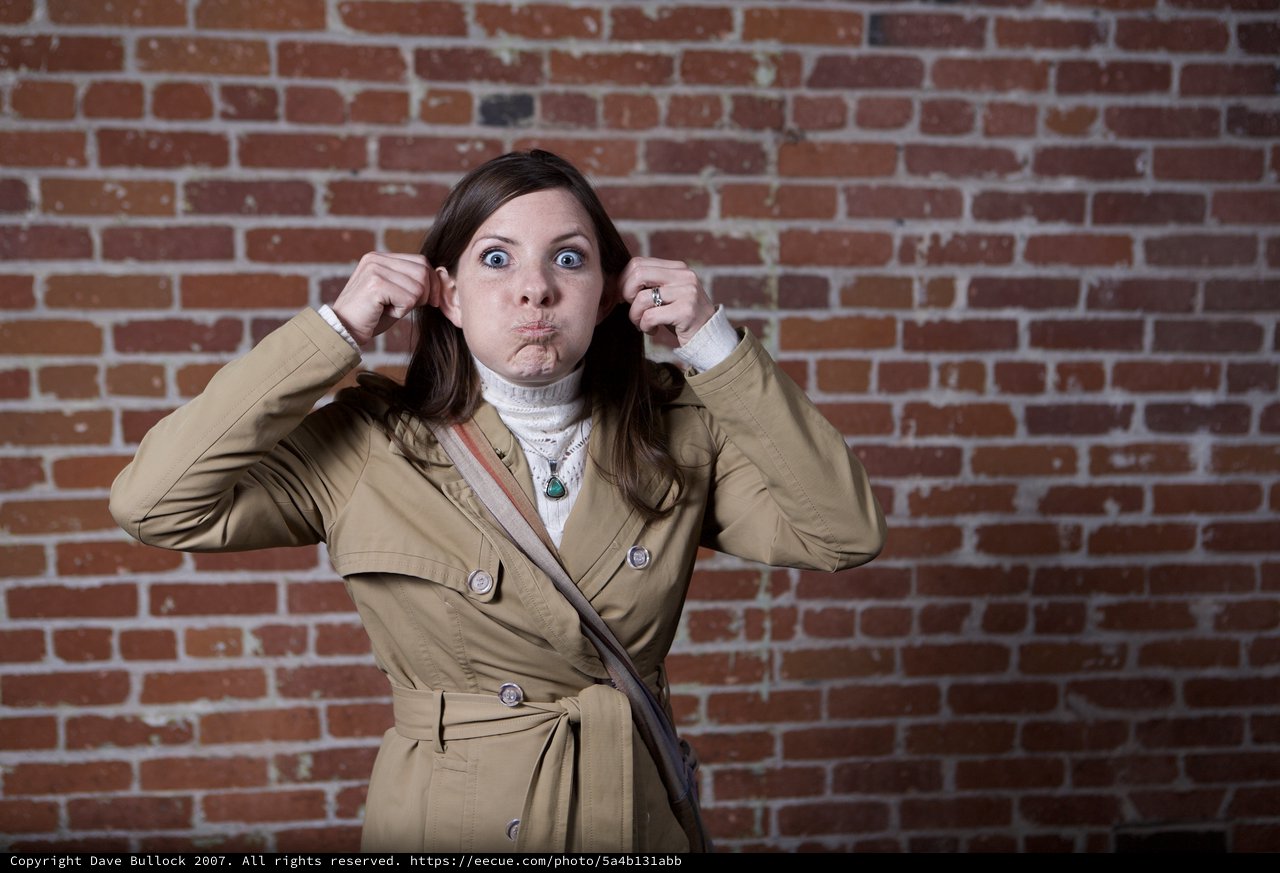 Playful Woman Makes Funny Face Against Brick Wall