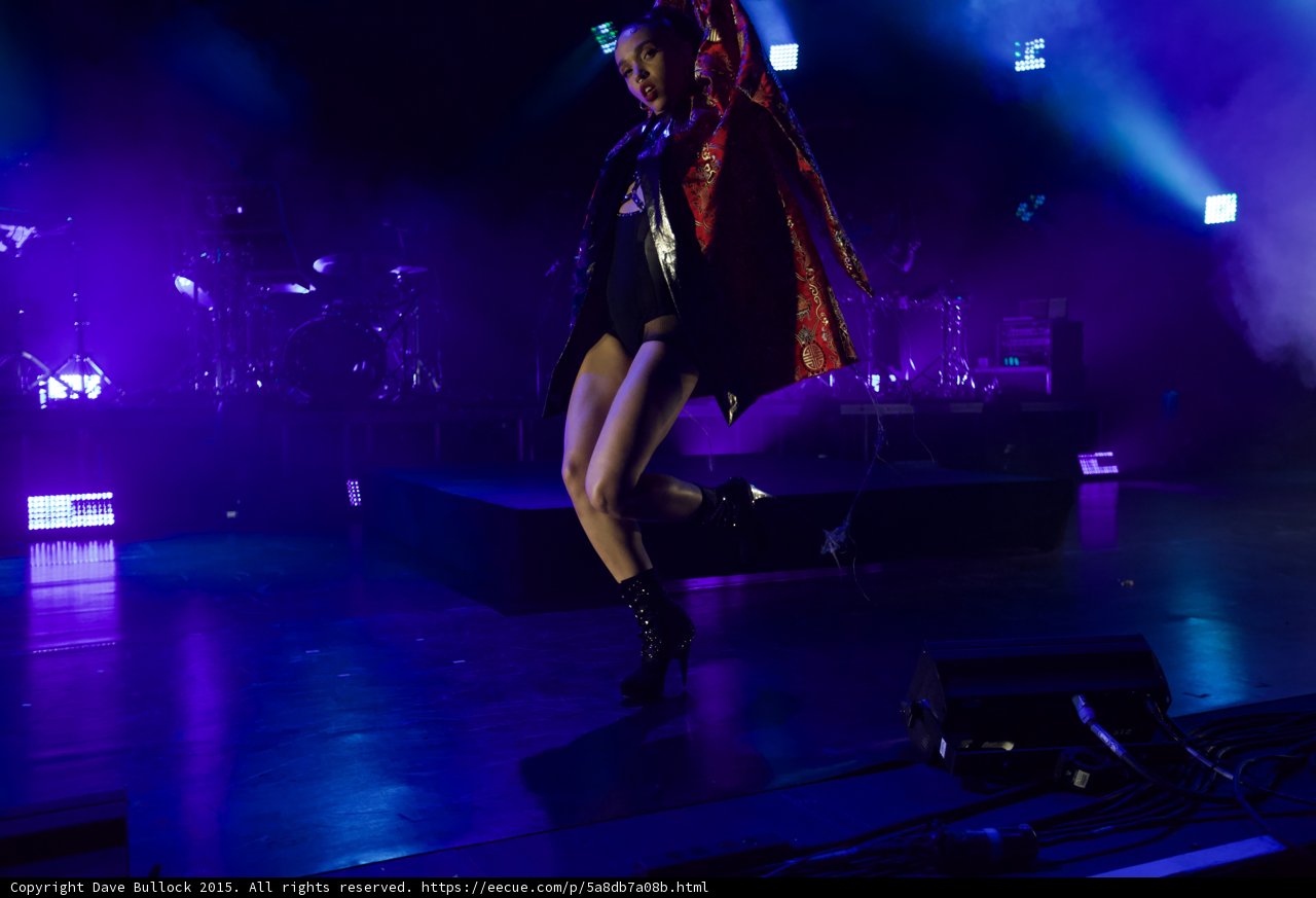 FKA twigs Full Body Dance Pose Leg Crossed Kimono Draped Shoulder Red Brocade Gold Patterns Black Bodysuit Boots Looking Down LED Panels Band