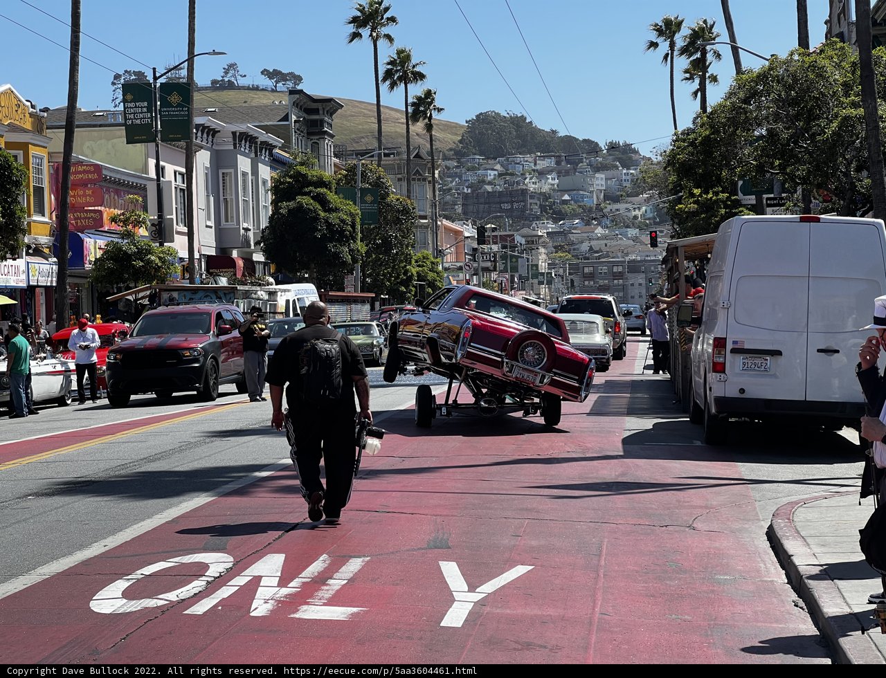 Man Transporting Car on Trailer Through Urban Streets