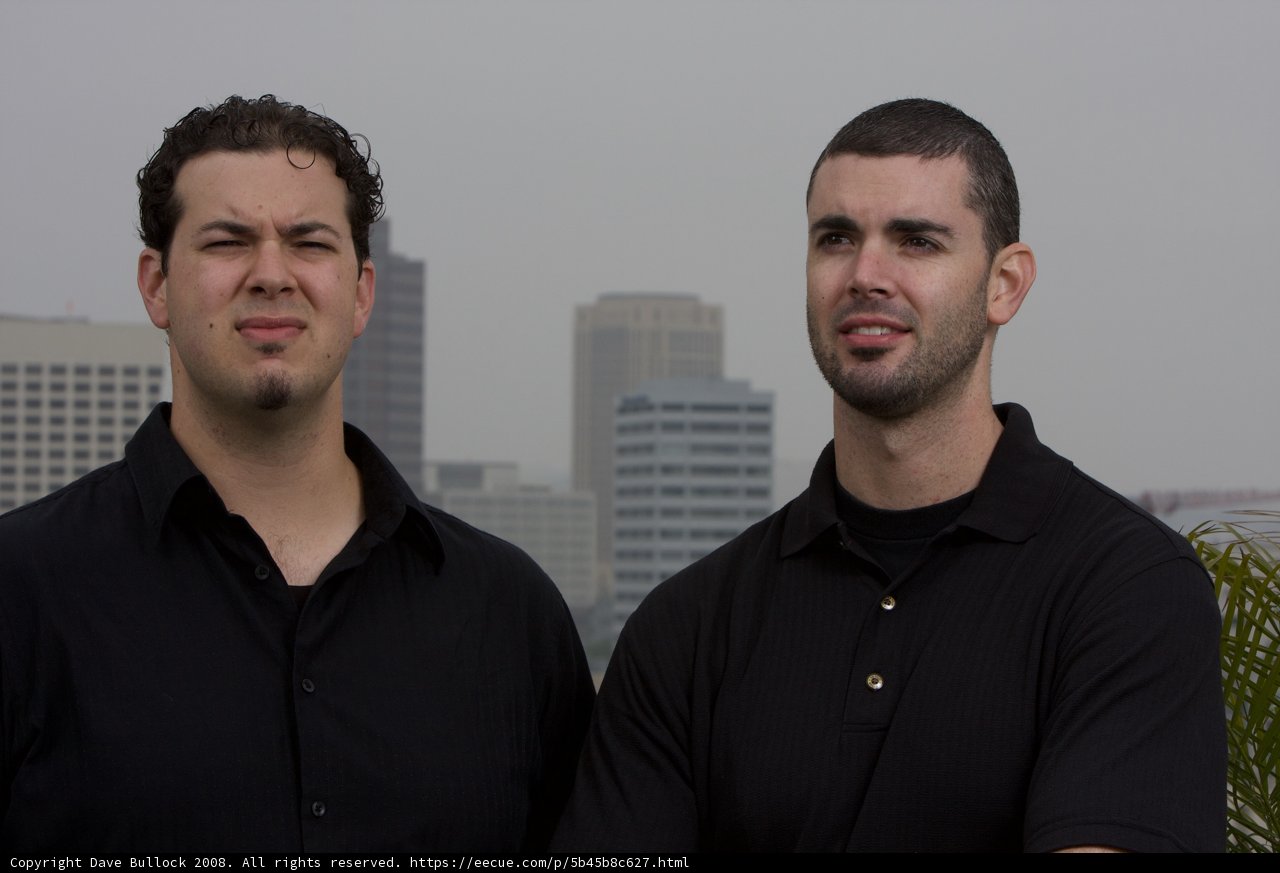 Two Men Smiling with Skyscraper in the Background