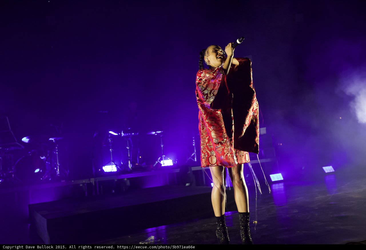 FKA twigs Full Body Singing Microphone Raised High Looking Up Passionately Kimono Red Brocade Gold Patterns Black Bodysuit Boots Purple Lighting White Haze LED Panels Band Drums