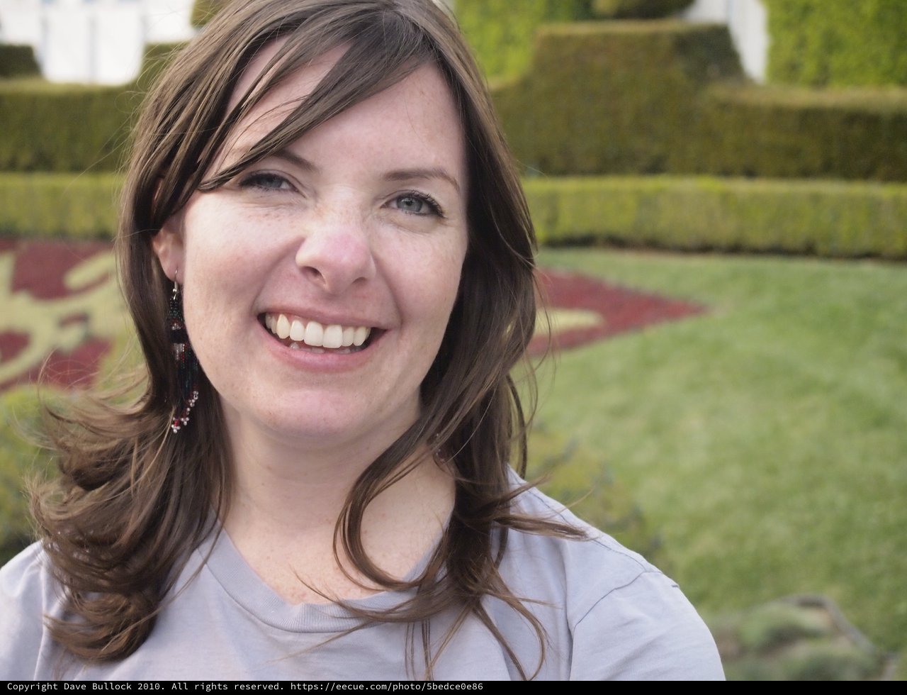 Joyful Woman Smiling in a Formal Garden Setting