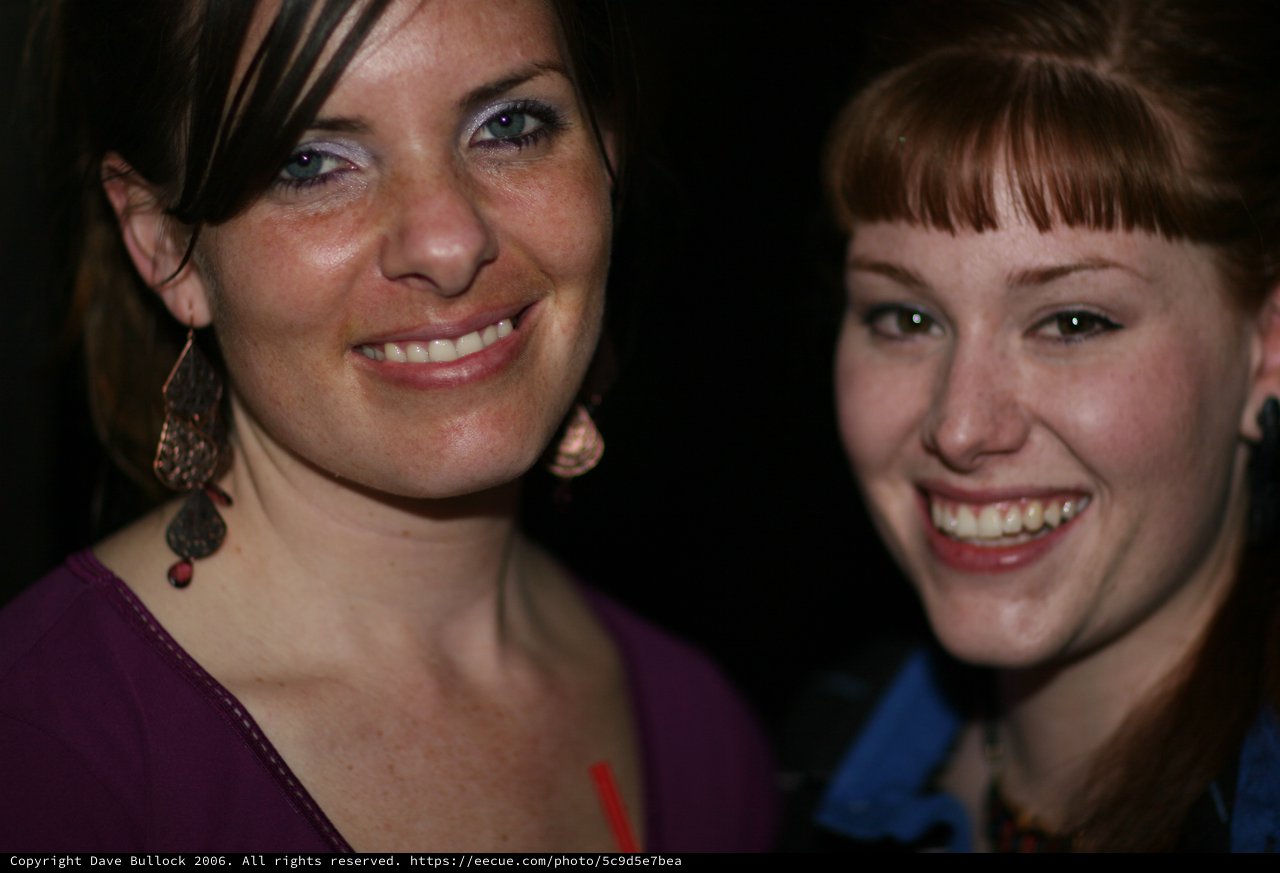 Two Smiling Women at a Nighttime Social Gathering