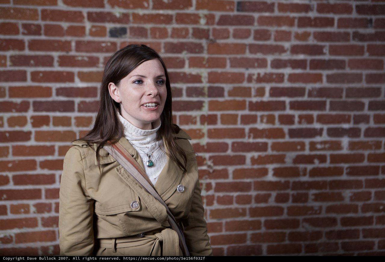 Woman in Trench Coat Against Rustic Brick Wall