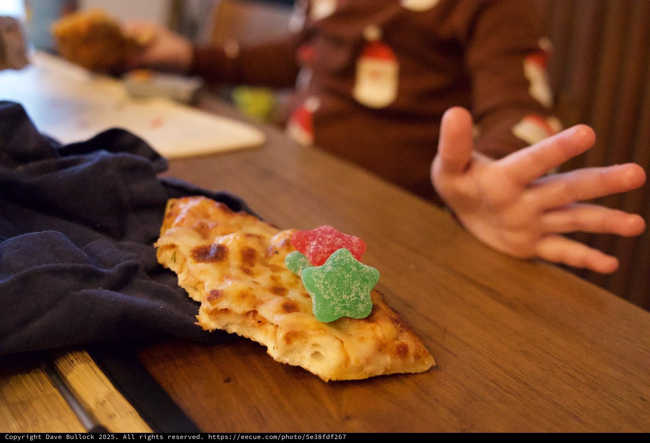 Child's Hand Reaching for Decorated Pizza Slice