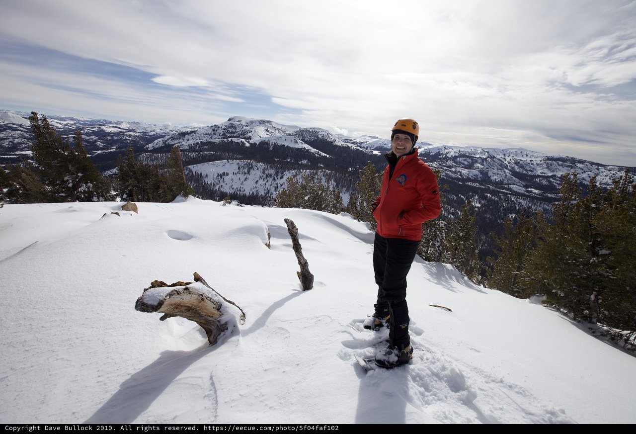 Summit Smiles: Winter Mountaineer Atop Snowy Peak